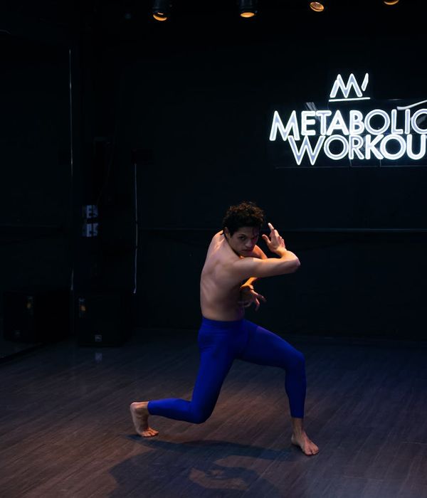 Man performing dynamic strength exercise in dark studio